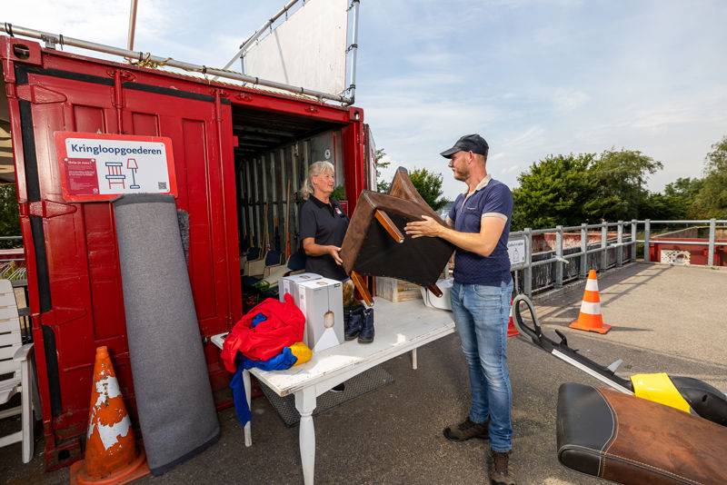 Collega Neemt Meubel Aan Voor Estafette Container Op Milieustraat Close Up LR Liggend
