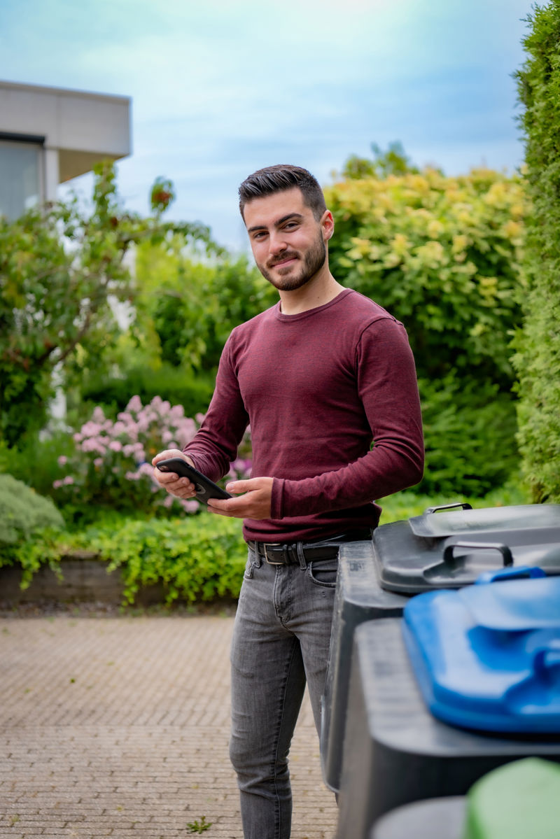 Man bij containers met telefoon in hand